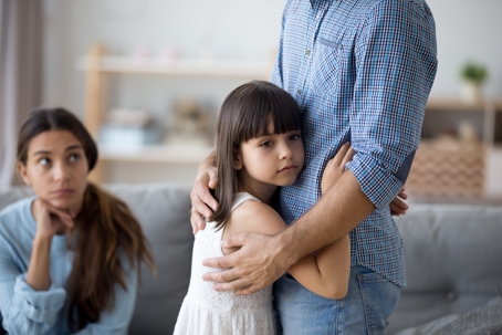 Daughter hugging father while mom looks upset