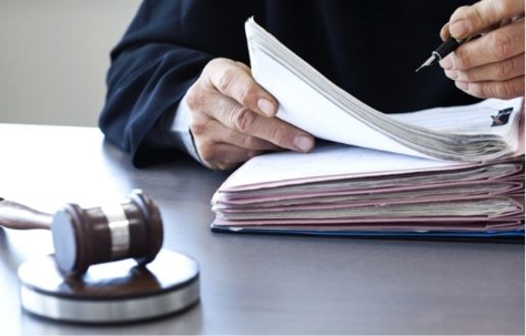 A gavel sits next to a stack of court documents. The photo likely accompanies legal content, maybe involving a court case or legal matter.